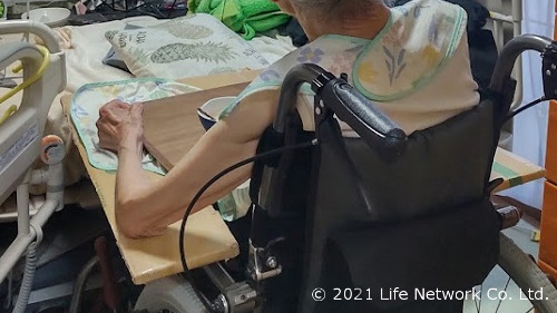 ダンボール箱で作った車椅子のテーブルで食事をしている様子
